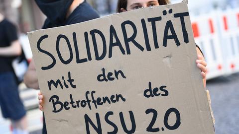 Eine Demonstrantin hält ein Pappschild mit der Aufschrift "Solidarität mit den Betroffenen der NSU 2.0".