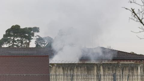 Rauchwolken über den Mauern und Stacheldrahtzäunen der Justizvollzugsanstalt Eberstadt.