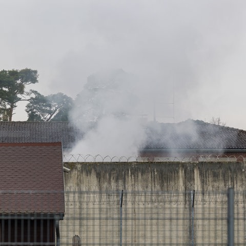 Rauchwolken über den Mauern und Stacheldrahtzäunen der Justizvollzugsanstalt Eberstadt.