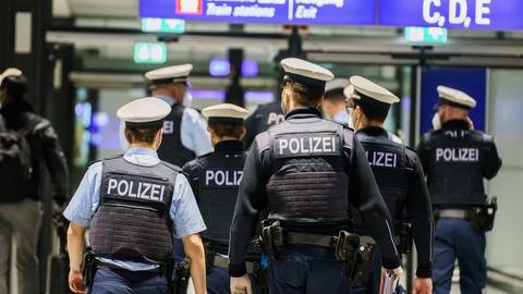 Beamte der Bundespolizei (von hinten) laufen durch die Schalterhalle des Frankfurter Flughafens.