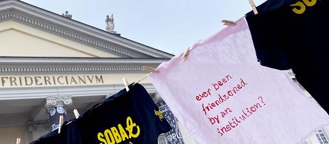 Beschriftete T-Shirts an der Leine aufgehängt vor dem Fridericianum in Kassel