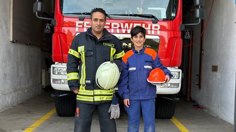 Ahmad und Siwar Kormo stehen vor dem roten Einsatzfahrzeug und schauen in die Kamera.