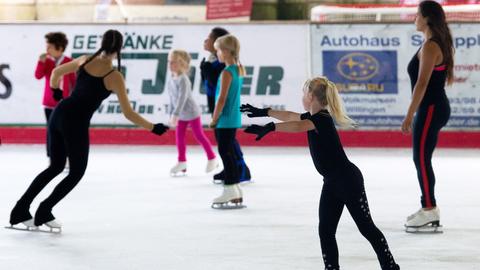 Junge Besucherinnen und Besucher fahren in der Eishalle in Willingen mit ihren Schlittschuhen über die Eisfläche.