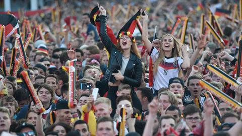 Eine Menschenmenge - viele tragen deutsche Fußballtrikots und schwenken Fahnen.