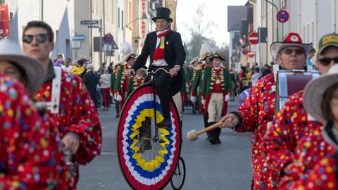 Ein verkleideter Mann auf einem Hochrad rollt als Teil des Fastnachtsumzugs durch die Straßen von Heddernheim.