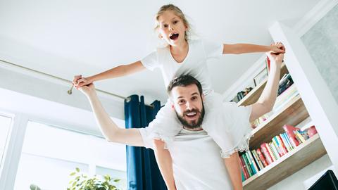 Mann mit Mädchen auf den Schultern in einer Wohnung