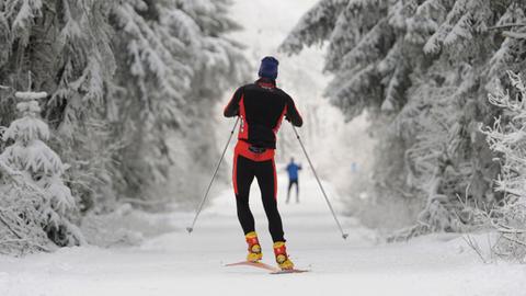 Langläufer skaten auf der Loipe auf dem nordhessischen Hohen Meissner in einer vor Eis und Schnee starrenden Winterlandschaft. 