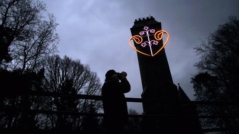 Ein neonfarbenes Herz leuchtet an einem Turm.