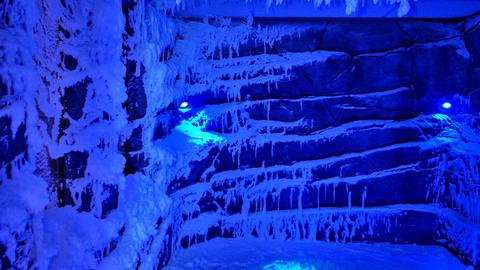 Eiszapfen hängen von der Decke der Schneekabine Marburg, auf dem Boden liegt Schnee.