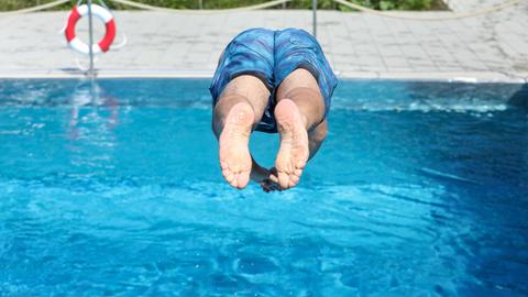 Mann springt kopfüber in ein Freibad