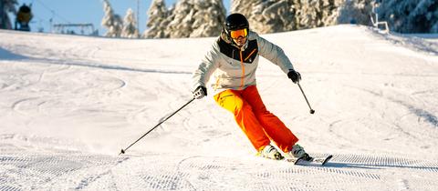 Ein Skifahrer fährt auf einer Skipiste auf der Wasserkuppe einen Hang hinab. 