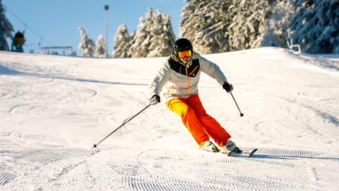 Ein Skifahrer fährt auf einer Skipiste auf der Wasserkuppe einen Hang hinab. 