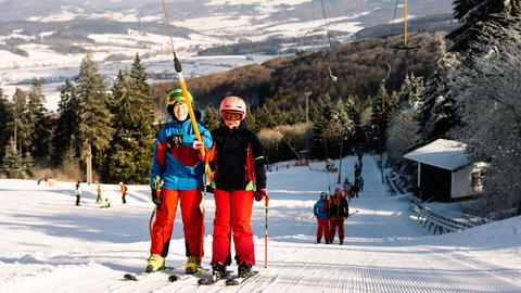 Skifahrer lassen sich mit einem Schlepplift an einer Piste auf der Wasserkuppe hinaufbefördern. 