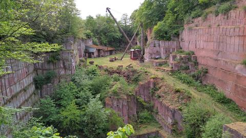 Der Steinbruch Michelnau, eine Art Grube, die von roten Steinen umrandet ist - im Hintergrund steht ein Holzkran.