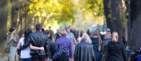 Menschen laufen durch eine herbstliche Allee.