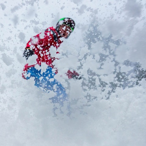 Skifahrer bremst, Schnee fliegt