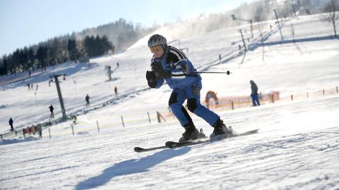 Ein Skifahrer - in der Mitte des Bildes - fährt eine Piste hinab.