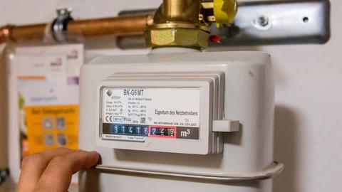Eine Hand an einem fachgerecht angeschlossenen Erdgaszähler für die Gastherme.