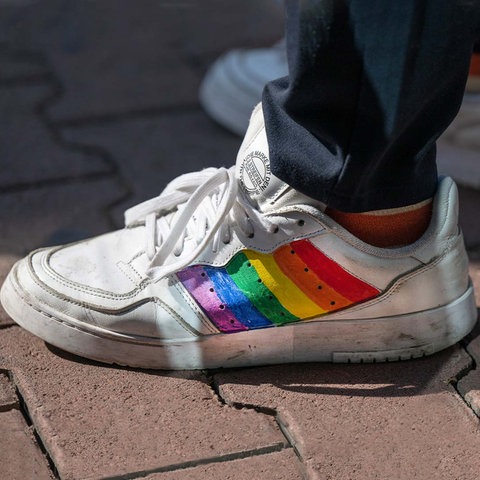 Kombination aus zwei Fotos: links Nahaufnahme Turnschuh in Regenbogenfarben angemalt, rechts Portrait von Abdelkarim Bendjeriou-Sedjerari.