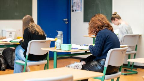 Schülerinnen sitzen während einer schriftlichen Prüfung in einem Klassenzimmer