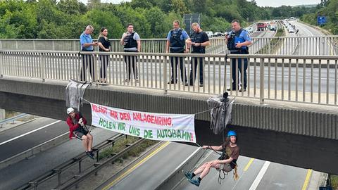 Verkehrswende-Aktivisten seilen sich von einer Brücke über der A485 bei Gießen ab.