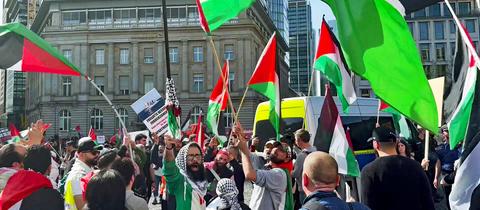 Teilnehmer der Demonstration schwenken palästinensische Flaggen.