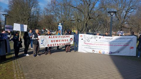 Demonstrierende Menschen mit Plakaten und Transparenten - Alevitische Gemeinde Gustavsburg steht auf einem der Transparente