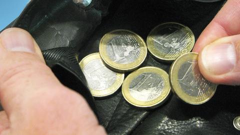 Ein-Euro-Stücke liegen in einer Geldbörse, die von zwei Händen offen gehalten werden.