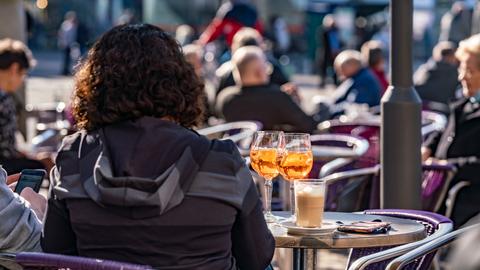 Besucher eines Straßencafes in Darmstadt genießen in der Innenstadt den Sonnenschein.