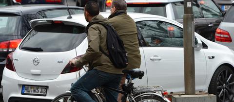 Zwei Radfahrer stehen in Frankfurt in einem Stau von Autos