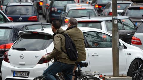 Zwei Radfahrer stehen in Frankfurt in einem Stau von Autos