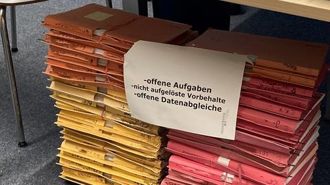 Aktenordner mit unbearbeiteten BAföG-Anträgen stapeln sich beim Studierendenwerk Frankfurt auf dem Boden unter einem Tisch