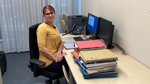 Lena Schmedes, Sachbearbeiterin beim Studierendenwerk Frankfurt, in ihrem Büro mit einem Stapel Akten neben sich und einem Computer vor sich