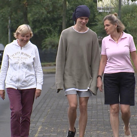 Ludmila, Jaroslaw und Svetlana laufen auf der Straße auf die Kamera zu.