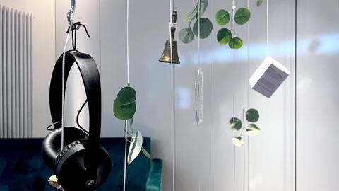 Detailaufnahme: Künstlerische Artefakte hängen an Fäden von der Decke.