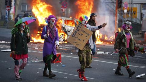 Demonstranten ziehen durch Frankfurt, im Hintergrund brennt ein Auto