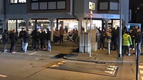 Menschen stehen in Grüppchen vor einer Bäckerei.