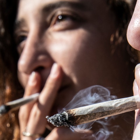 Zwei Frauen rauchen einen Joint.