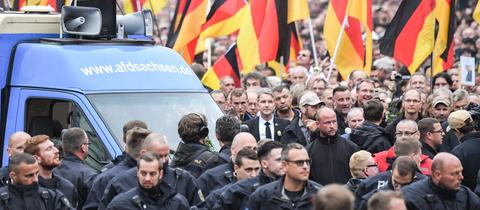 Demonstrationszug der AfD mit Deutschlandfahnen, mittendrin Björn Höcke in schwarzem Anzug und schwarzer Krawatte