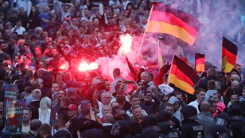 Pyrotechnik wird in einer Demonstration gezündet, mehrere Deutschlandfahnen und Schilder "Asylflut stoppen"