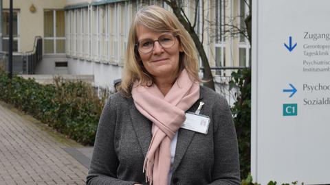 Claudia Gutmann steht vor dem Klinikum und lächelt in die Kamera.