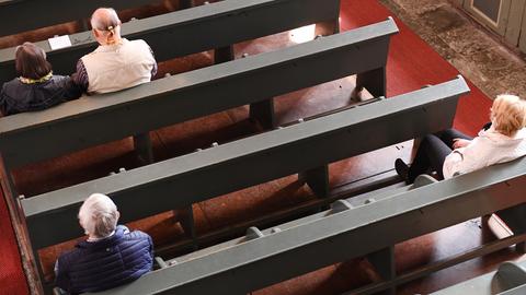 Gottesdienstbesucher mit Abstand auf den Bänken einer Kirche