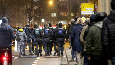 In der Dunkelheit gehen viele Menschen auf der Straße, darunter einige Polizisten - alle von hinten fotografiert. 