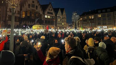 Menschen halten bei der Demo gegen rechts auf dem Frankfurter Römerberg abends Lichter in die Höhe.