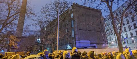 Demonstranten am Sonntagabend vor der Dondorf-Druckerei in Frankfurt, auf dem Dach sind Besetzer zu erkennen.