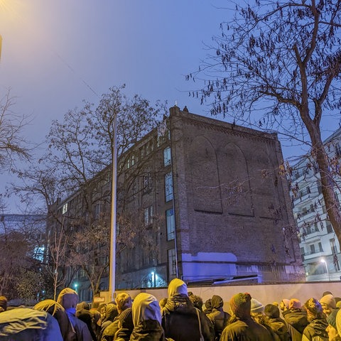 Demonstranten am Sonntagabend vor der Dondorf-Druckerei in Frankfurt, auf dem Dach sind Besetzer zu erkennen.