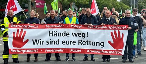 Demonstration von Einsatzkräften mit Banner "Hände weg!"