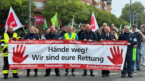 Demonstration von Einsatzkräften mit Banner "Hände weg!"