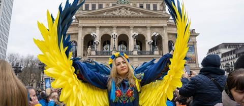 Demonstrantin vor der Alten Oper in Frankfurt - mit Flügeln in ukrainischen Farben