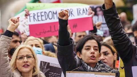 Menschen recken ihre Fäuste vor einem Plakat mit der Aufschrift "Freedom for Iran".